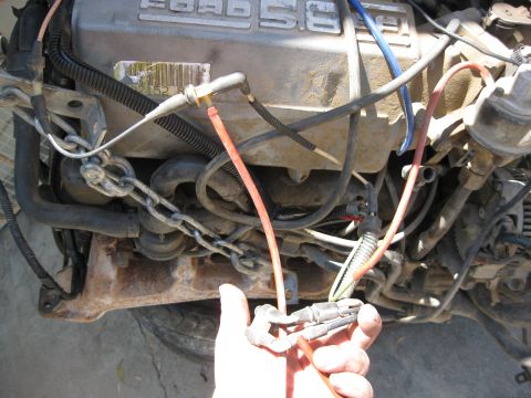 1969 Ford F-250 - Close-up of a Ford 5.8L engine, showing wiring and chains, with a hand holding electrical connectors.