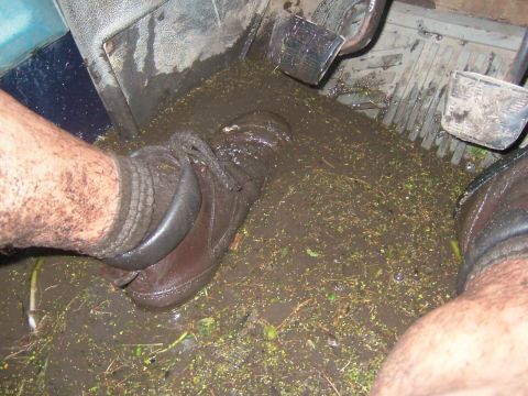 1978 Chevrolet C/K Pickup - The interior of a vehicle is flooded with mud and debris, obscuring the pedals and floor.