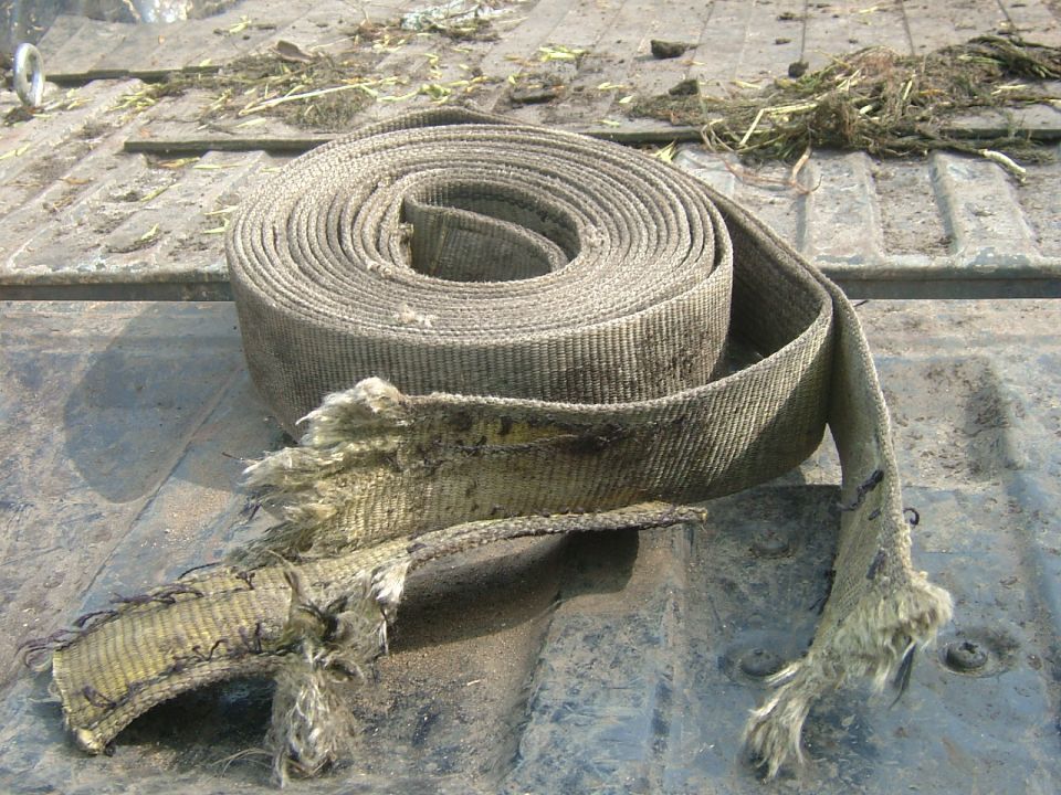 Rolled up, frayed tie-down strap on a truck bed