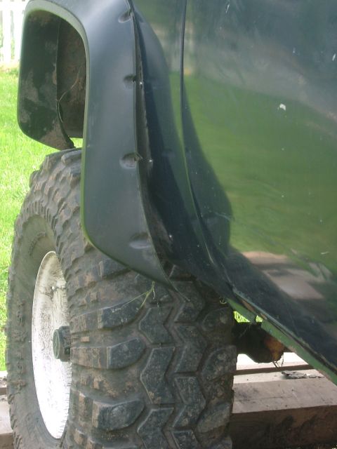 1978 Chevrolet C/K Pickup - Close-up view of a dark green pickup truck's fender flare and aggressive off-road tire.