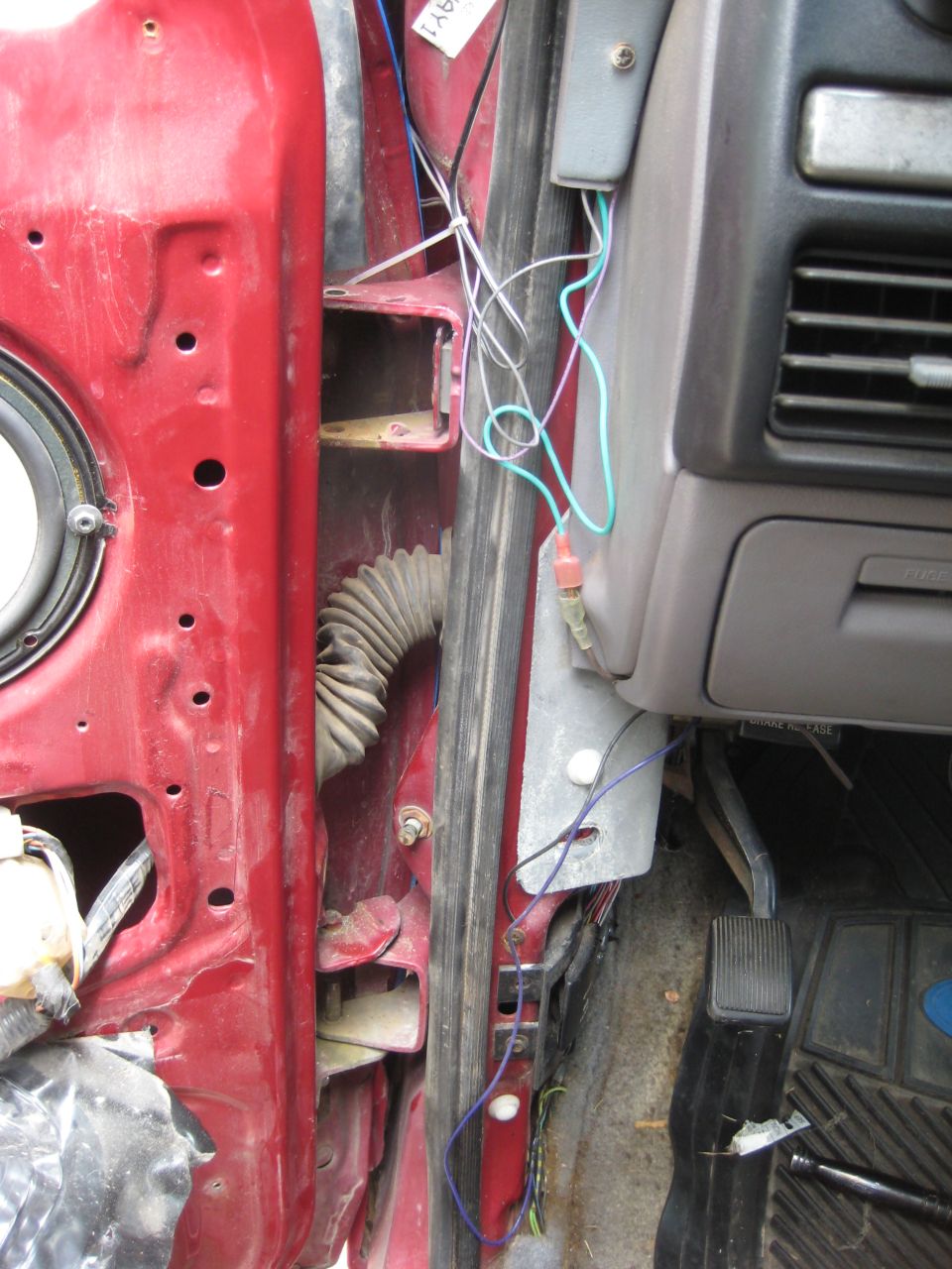 Close-up of a car's red door jamb with exposed wiring and a rubber conduit