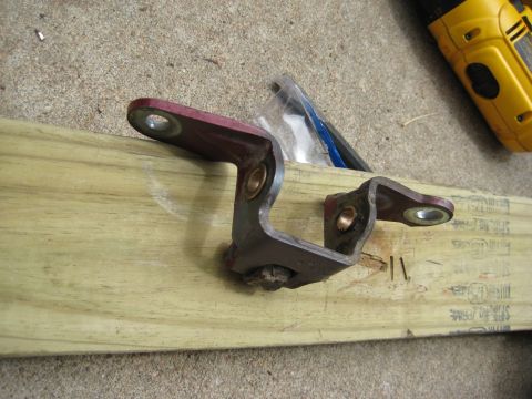 1995 Ford Bronco - A single door hinge part is shown mounted on a wooden plank, with a yellow power tool visible in the background.
