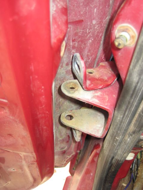 1995 Ford Bronco - Close-up view of red door hinges, likely from a vehicle's door frame.