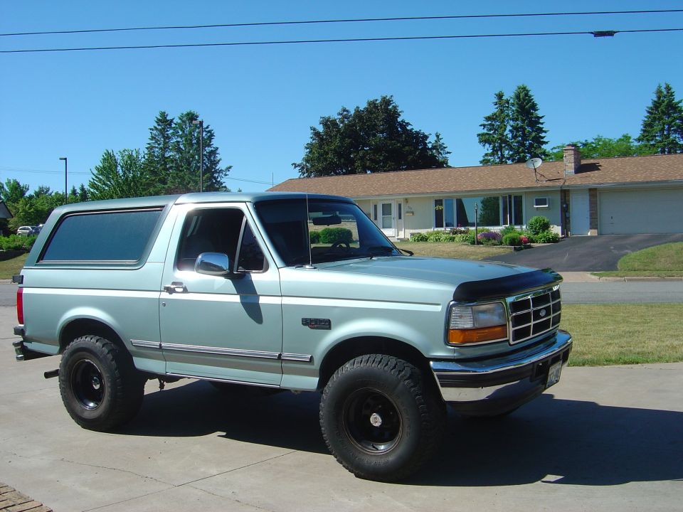 1996 Ford Bronco parked in front of a house on a sunny day