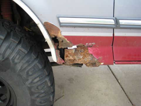 1995 Ford Bronco - Significant rust has eaten away at the lower body panel of this vehicle, compromising its structural integrity.