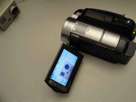 1993 Ford Taurus - A camcorder and an action camera are placed on a flat surface, with the camcorder's screen displaying a preview of the action camera.
