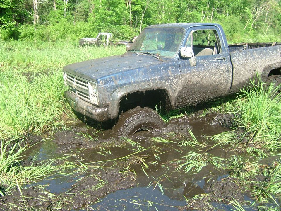 1978 Chevrolet C/K Pickup stuck in mud with another truck in the background