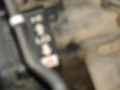 1989 Yamaha MOTO-4 - A close-up view shows a black component with directional arrows and a small red label, likely a control or indicator.