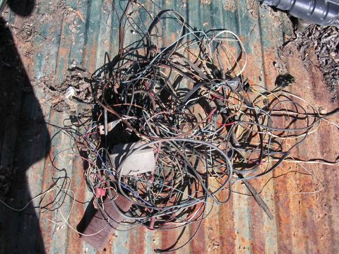 1978 Ford Bronco - A messy bundle of electrical wires lies on a weathered, corrugated metal surface.