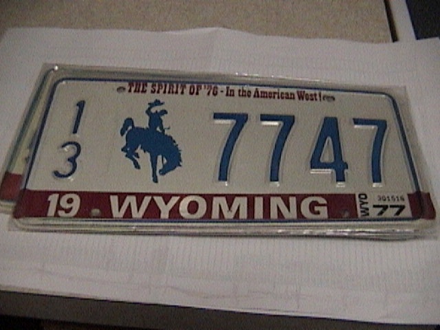 Vintage 1977 Wyoming license plate 13 7747 with bucking horse emblem in chrome frame