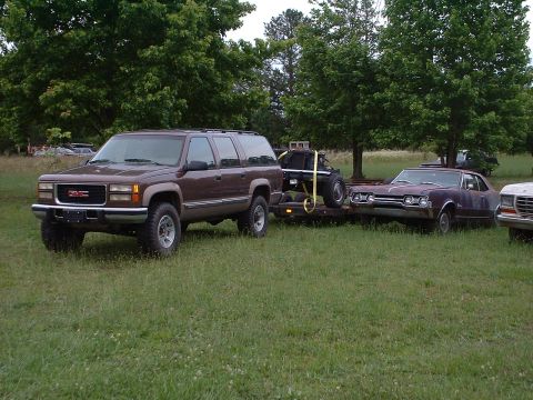 1994 GMC Suburban - Brown 1995 GMC Suburban is seen towing a trailer with a maroon car on it.
