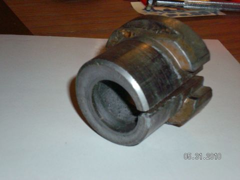 1996 Ford Bronco - Close-up of a removed metal sleeve bushing sitting on white paper over a wood table, showing a split slot down its side and light surface r…