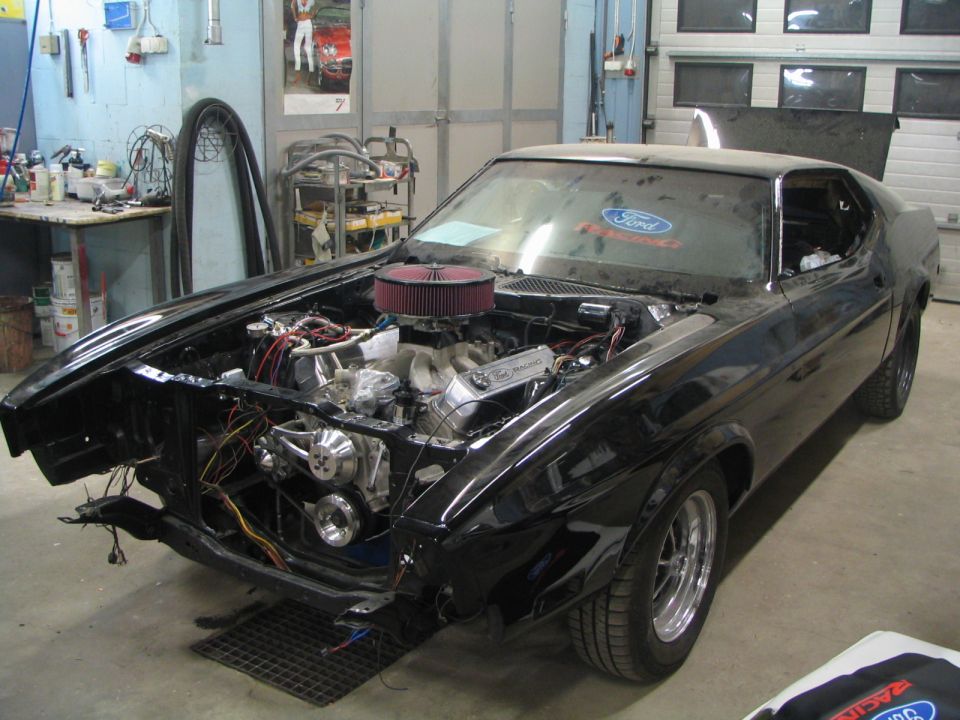 1971 Ford Mustang in garage, hood open, engine exposed. Ford Racing valve covers visible