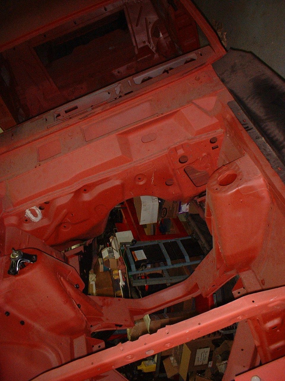 Stripped red-primer engine bay of a car shell shot from above during restoration