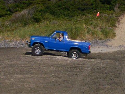 1980 Ford Bronco - This blue 1980 Ford Bronco is captured in a three-quarter front view as it navigates a sandy terrain.