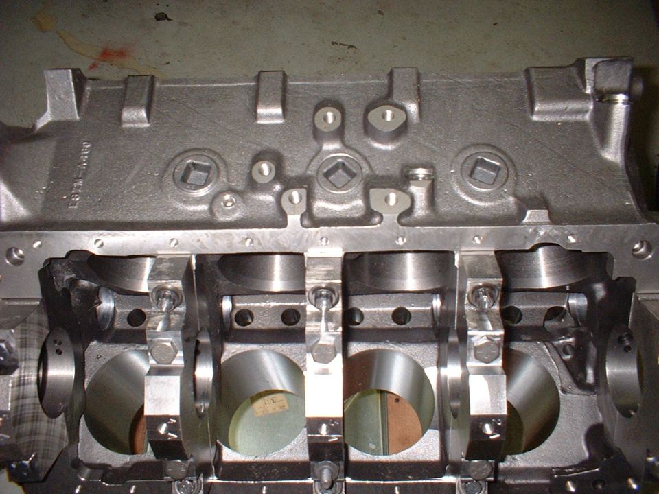 Engine block with crankshaft bearings visible, showing machined surfaces and bolts
