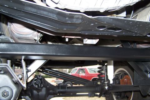2000 Ford F-150 - A close-up of a vehicle's undercarriage, with a red SUV visible in the distance.