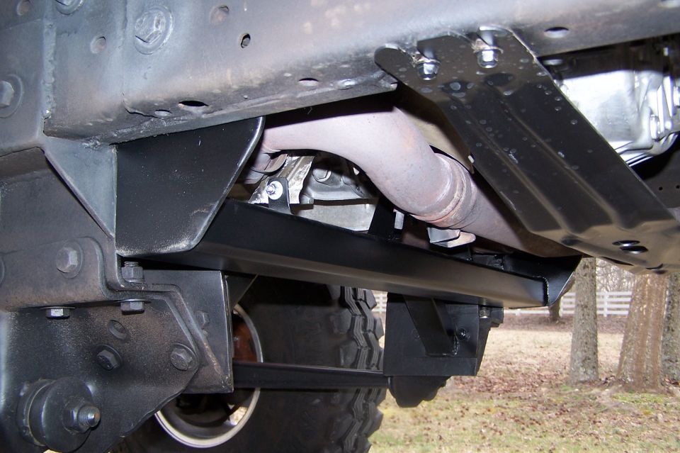 Fabricated black crossmember bolted between truck frame rails under a lifted truck
