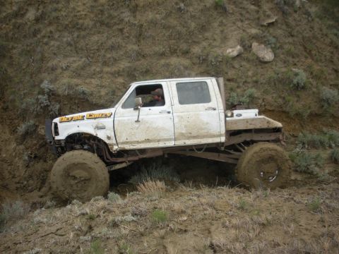 1992 Ford F-350 - This modified 1992 Ford F-350 crew cab with a flatbed and oversized tires navigates a challenging muddy terrain.