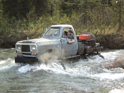 1990 Chevrolet Suburban - This modified pickup truck navigates a rocky riverbed, its off-road capabilities.