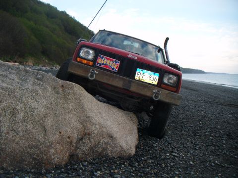 1998 Jeep Cherokee - This Jeep Cherokee is positioned on a rocky shoreline, with one wheel resting on a large stone.