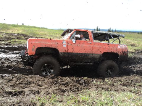 1990 Chevrolet Suburban - This modified truck is deep in the mud, showing its off-road capabilities.