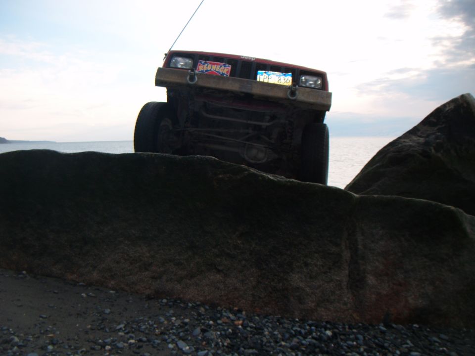 Red 1998 Jeep Cherokee on rocks near water