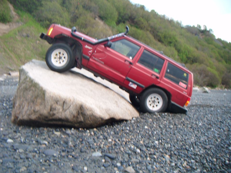 Red 1998 Jeep Cherokee on a rock with snorkel and off-road lights