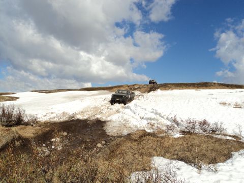 1990 Chevrolet Suburban - Off-road vehicles traverse a snow-covered landscape with dry grass and sparse bushes.