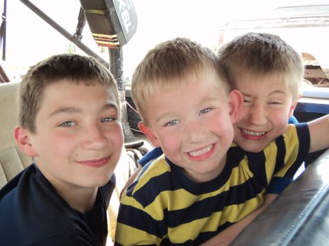 1990 Chevrolet Suburban - Three smiling boys are captured in a close-up photo, possibly inside a vehicle.