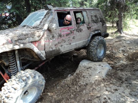 1990 Chevrolet Suburban - This heavily modified SUV navigates a challenging off-road course, covered in mud.