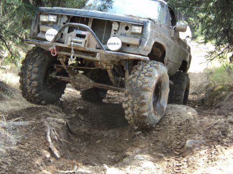 1990 Chevrolet Suburban - Modified pickup truck tackling a challenging off-road course with mud and obstacles.