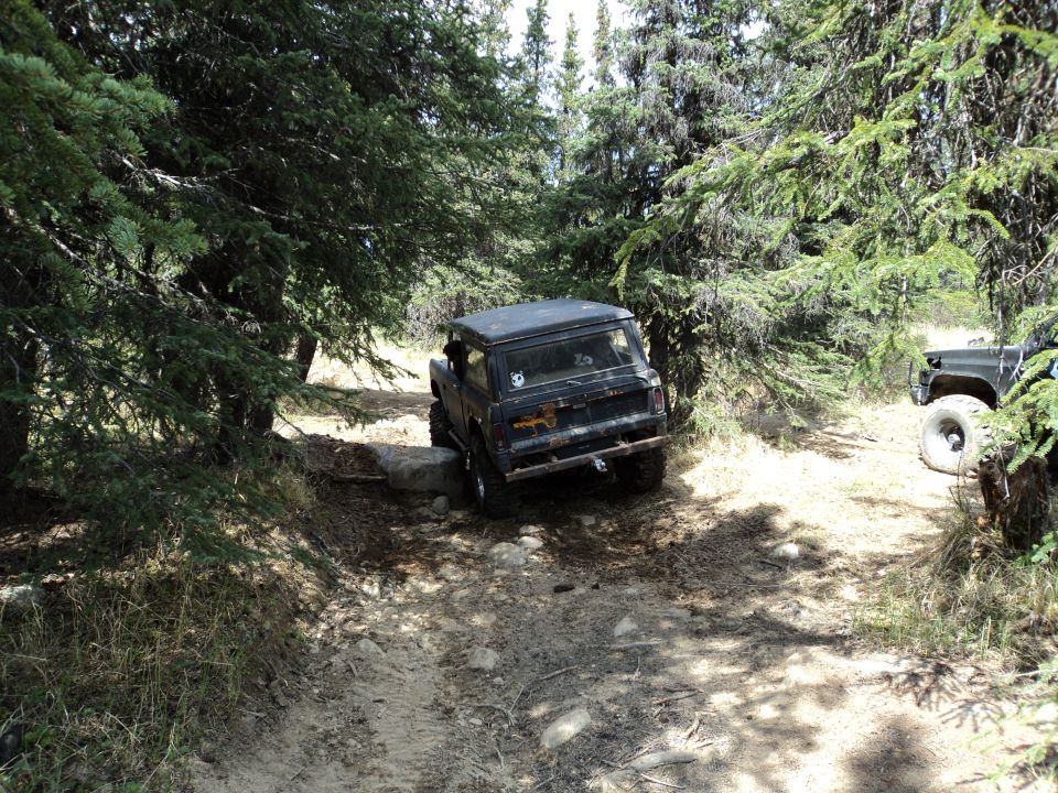 Black SUV with rust on the rear bumper, navigating a rocky trail
