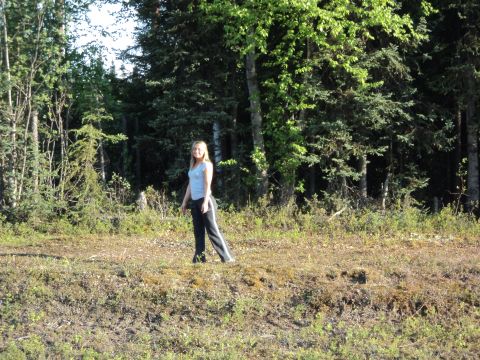 1990 Chevrolet Suburban - A woman stands in a clearing surrounded by trees, with a Supermotors.net logo visible.