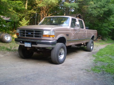 1979 Ford Bronco - This lifted Ford F-Series truck is parked on a dirt road with trees in the background.