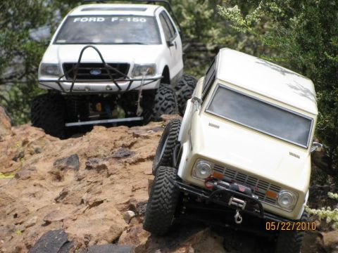 1988 Ford Bronco - Two RC off-road vehicles, a 1988 Ford Bronco and a Ford F-150, navigate a rocky trail.