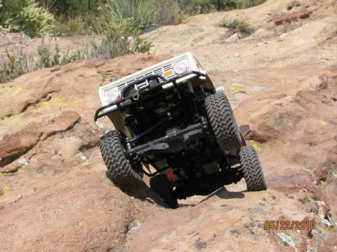 1988 Ford Bronco - A white 1988 Ford Bronco navigates a rocky incline, its off-road capabilities.