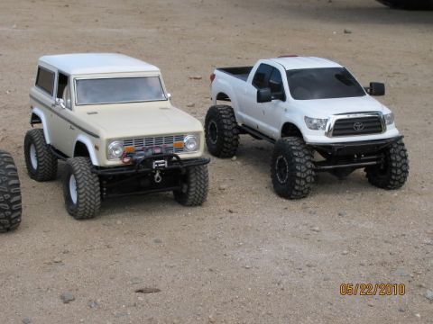 1988 Ford Bronco - RC off-road vehicles, a Bronco and a Tundra, sit on a dirt surface.