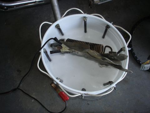 1979 Ford F-250 - A setup for electrolysis rust removal is shown in a white bucket with various components.