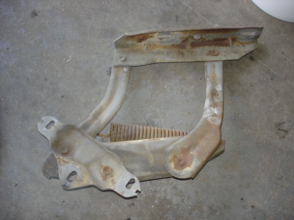 Rusted hood hinge assembly with spring, likely for a truck