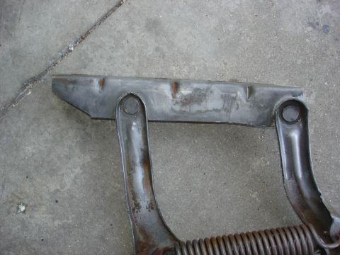 1979 Ford F-250 - A metal component, possibly a hinge or bracket, rests on a concrete surface, exhibiting signs of rust and age.
