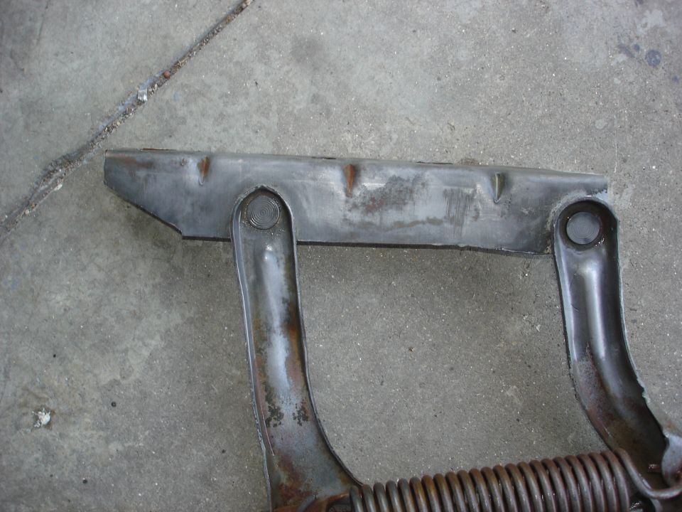 Metal part with spring on concrete, showing rust and wear