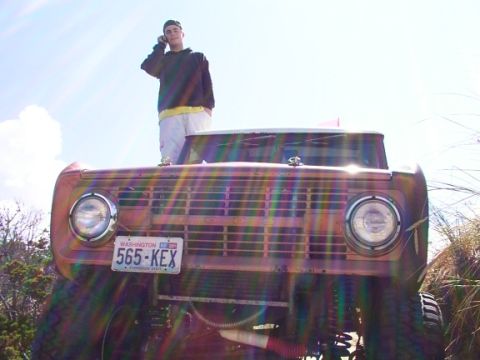 1980 Ford Bronco - A person stands atop a vintage Ford Bronco, holding a phone to their ear.