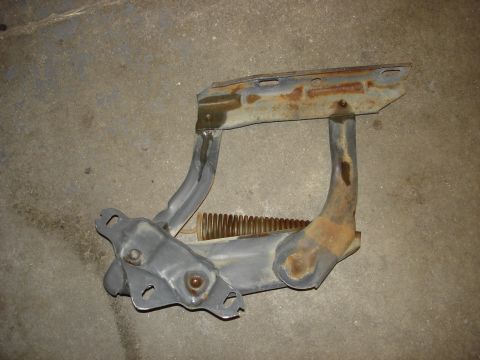 1979 Ford F-250 - A rusty hood hinge assembly, likely from an older truck, is shown against a concrete floor.