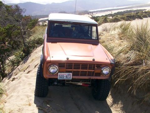 1980 Ford Bronco - Ford Bronco navigates a sandy incline with coastal scenery in the background.