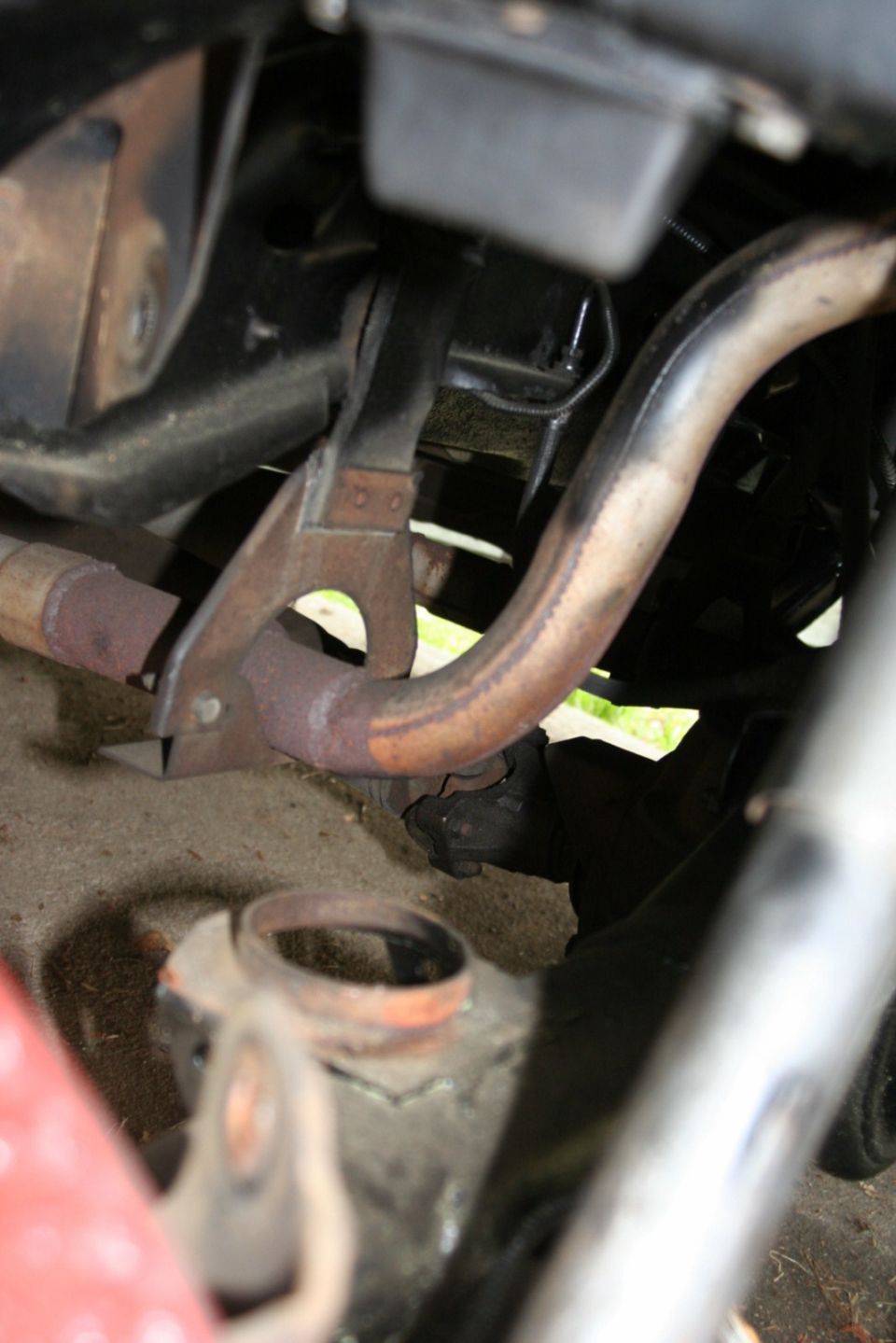 Close-up of rusted exhaust pipe and metal bracket under a vehicle