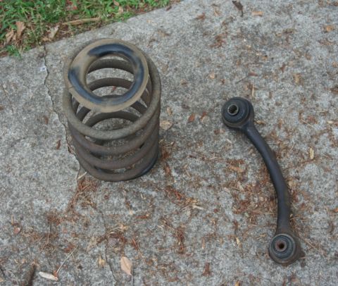 1976 Ford Ranchero - Suspension components, including a coil spring and a control arm, lie on a concrete surface.