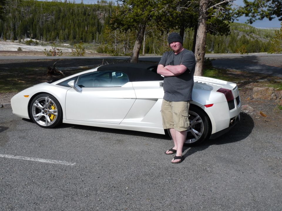 Guy in beanie and shorts leaning on a white convertible sports car