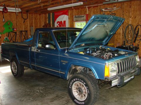 1991 Jeep Comanche - Blue 1991 Jeep Comanche pickup truck with hood open, parked inside a garage.
