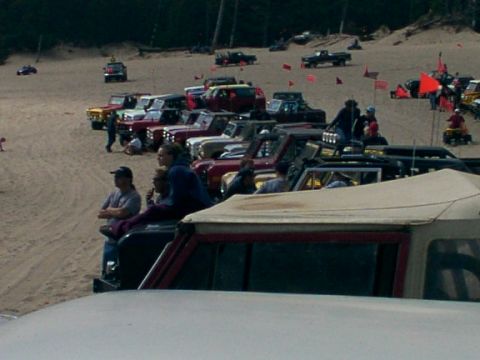 1980 Ford Bronco - A gathering of off-road vehicles and people on a sandy terrain, possibly a dune buggy event.
